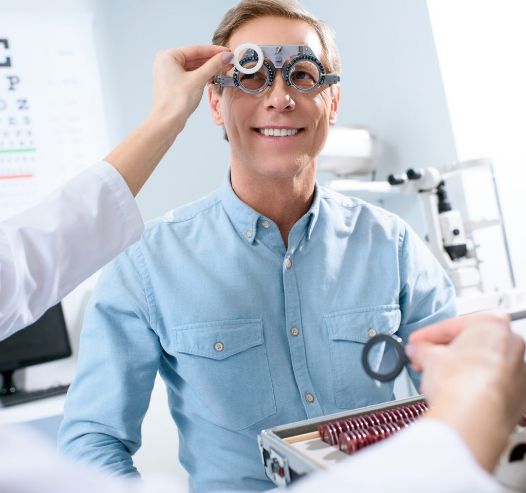 optometrist examining man's eyes with trial-frame